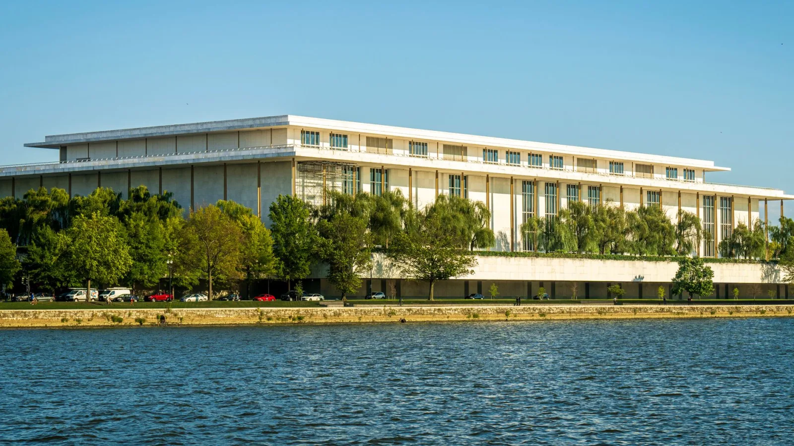 Captivating view of the Kennedy Center beside the Potomac River with lush greenery in summer.