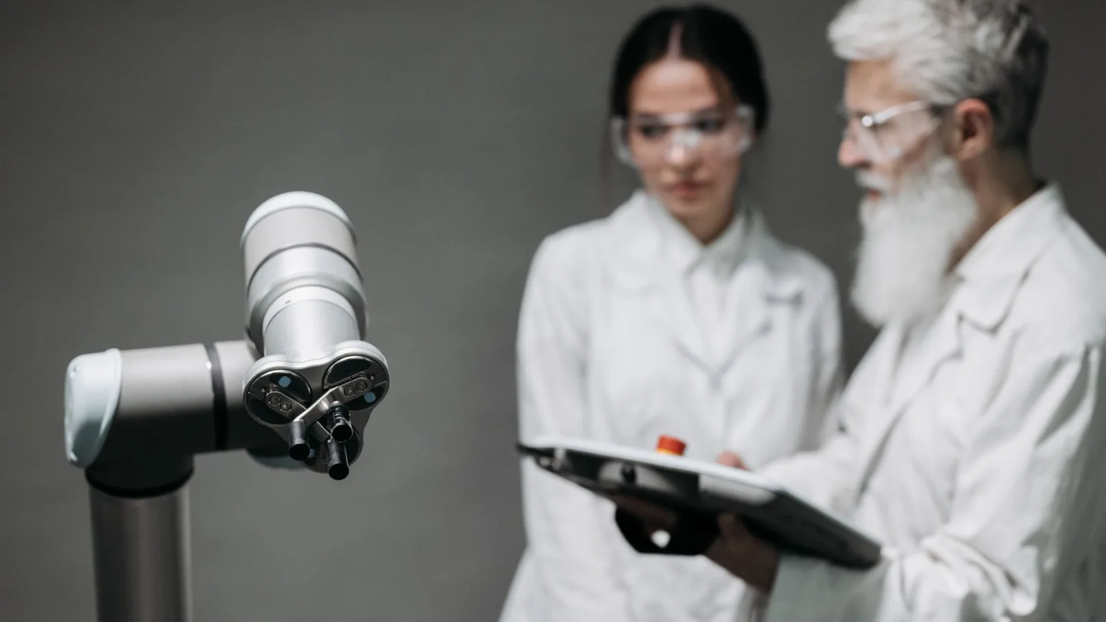 Researchers in lab coats analyze robotic equipment for technological advancement.