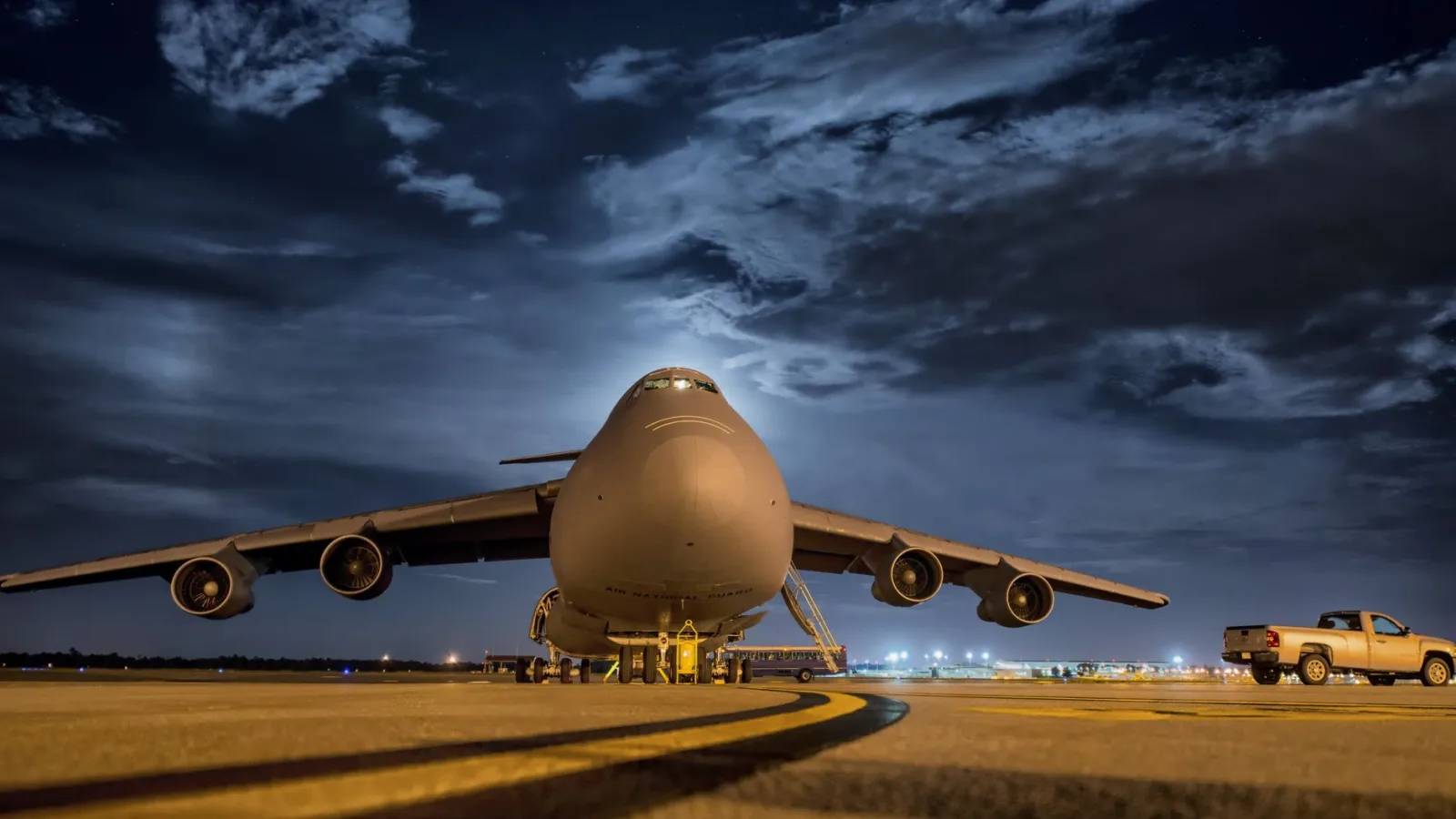 A large cargo plane stationed on the tarmac under the night sky, ready for transport.